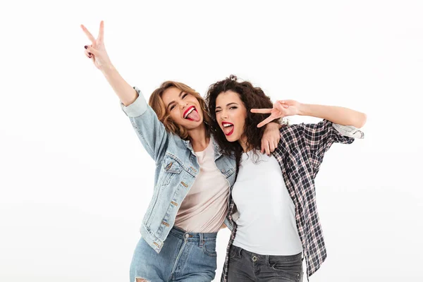 Imagen de dos chicas juguetonas de pie juntas y mostrando la paz — Foto de Stock