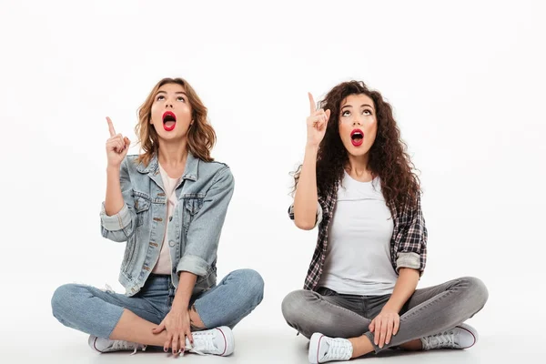 Dos chicas sorprendidas sentadas en el suelo juntas —  Fotos de Stock