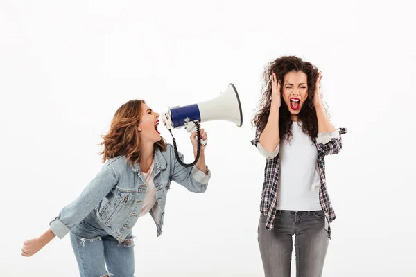 Confused curly woman covering her ears while second girl screaming — Stock Photo, Image