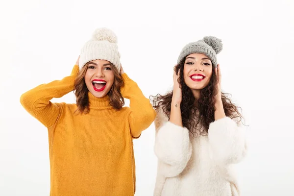 Duas meninas engraçadas em camisolas e chapéus se divertindo juntos — Fotografia de Stock