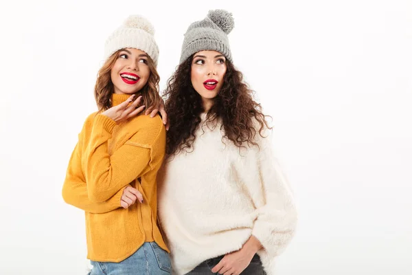 Дві усміхнені дівчата в светрах і капелюхах стоять разом — стокове фото
