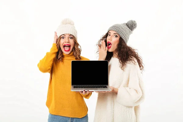 Две шокированные девушки в свитерах и шляпах стоят вместе — стоковое фото