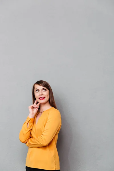 Portrait of a smiling woman looking up way at copy space isolated over gray background — Stock Photo, Image