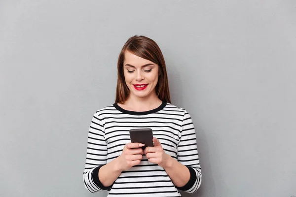 Retrato de uma mulher sorrindo mensagens de texto no telefone celular — Fotografia de Stock