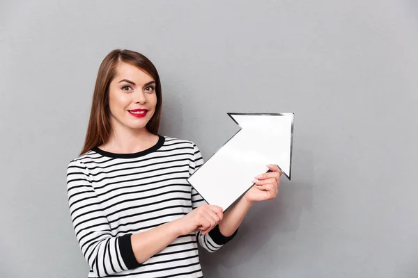 Portrait of a smiling woman pointing paper arrow up — Stock Photo, Image