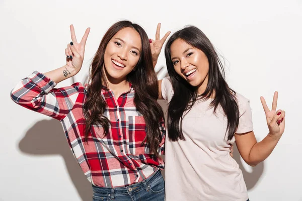Dvě asijské sestry docela veselé ženy ukazující míru gesto. — Stock fotografie