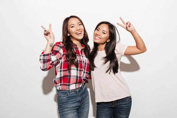 Due asiatico grazioso allegro signore sorelle mostrando pace gesto . — Foto Stock