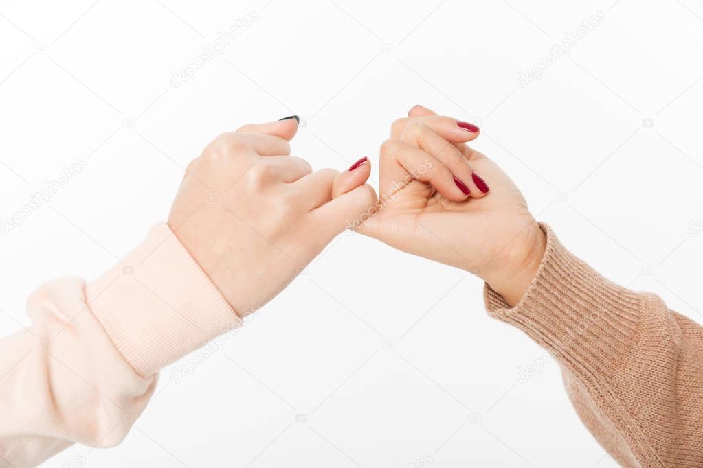 Two hands hook each other's little finger