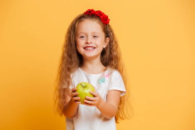 Mutlu küçük kız çocuğu elma tutan gülümseyerek.