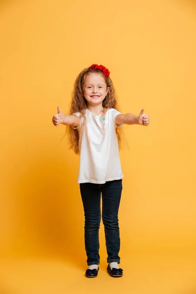 Sonriente niña pequeña mostrando los pulgares hacia arriba . — Foto de Stock