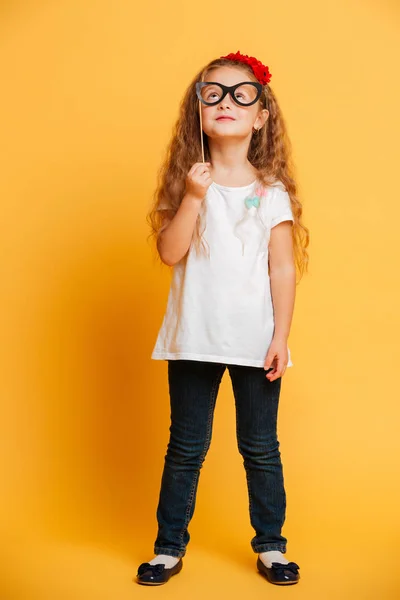 Graciosa niña sosteniendo gafas falsas mirando a un lado . — Foto de Stock
