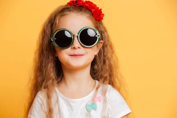 Μικρό χαριτωμένο χαμογελαστό κορίτσι φορώντας γυαλιά ηλίου που ψάχνει τα φωτογραφικών μηχανών. — Φωτογραφία Αρχείου
