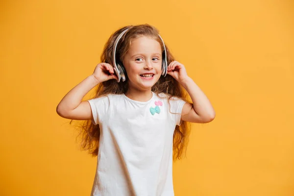 Chica feliz de pie escuchando música aislada con auriculares . — Foto de Stock