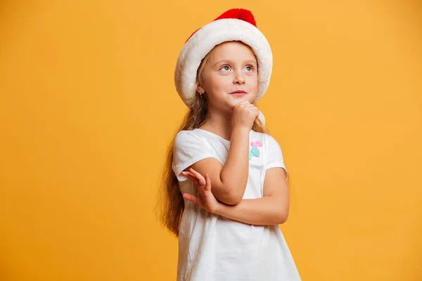 Chica reflexiva de pie aislado usando sombrero de navidad santa . — Foto de Stock