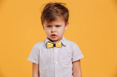 Üzgün küçük çocuk çocuk üzerinde sarı izole ayakta