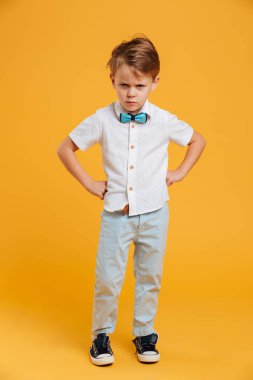 Kızgın küçük çocuk çocuk üzerinde sarı izole ayakta