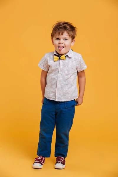 Маленький мальчик стоял изолированный показывая язык . — стоковое фото