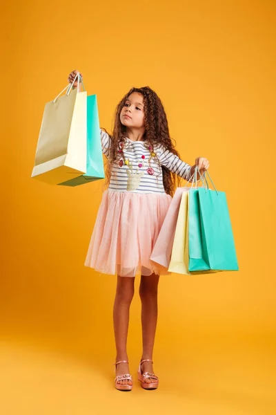 Gondolkodó lány gyermek gazdaság bevásárló táskák. — Stock Fotó