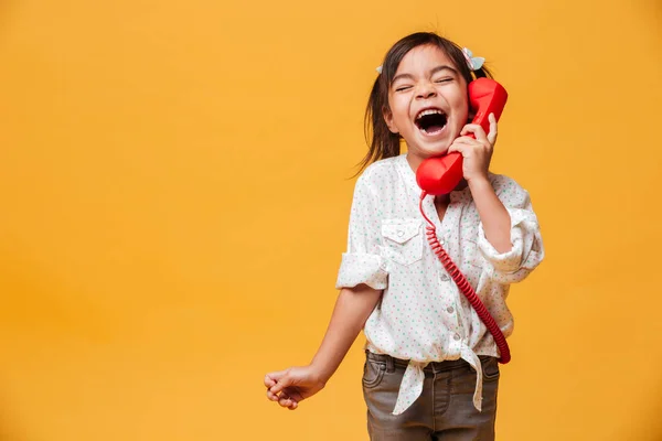 Gritando animado menina criança falando por vermelho retro telefone . — Fotografia de Stock