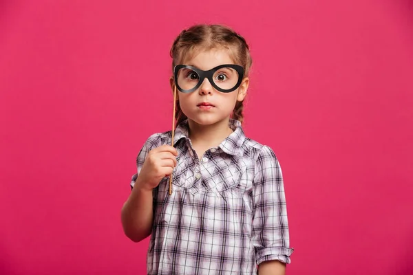 Menina chocada criança segurando óculos falsos . — Fotografia de Stock