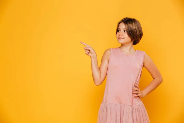 Pequeña chica confiada apuntando al espacio de copia aislado —  Fotos de Stock