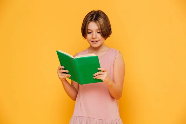 Vrolijk meisje lezen boek geïsoleerd over geel — Stockfoto