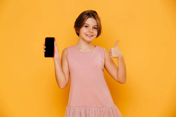 Hermosa chica en vestido rosa mostrando el teléfono inteligente y el pulgar hacia arriba aislado —  Fotos de Stock