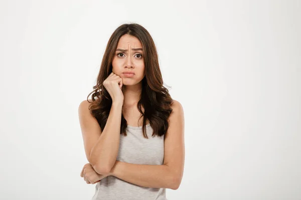 Confused brunette woman with arm near chin looking at camera — Stock Photo, Image