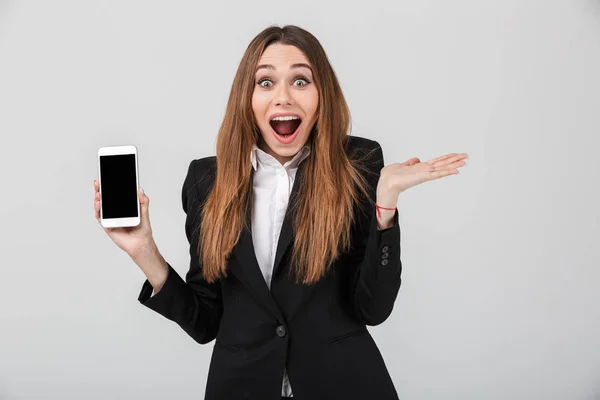 Senhora bonita com boca aberta e mostrando smartphone com tela em branco isolado — Fotografia de Stock