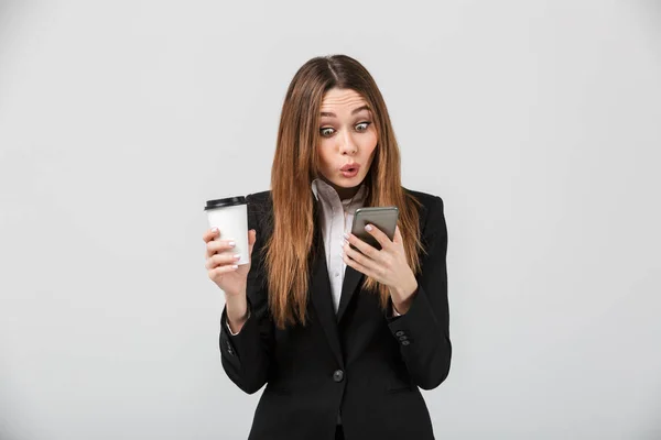 Chocado senhora bate-papo no smartphone e segurando xícara de café isolado — Fotografia de Stock