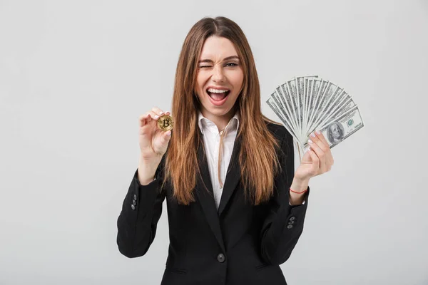 Cheerful young woman showing golden bitcoin and dollars in hands — Stock Photo, Image