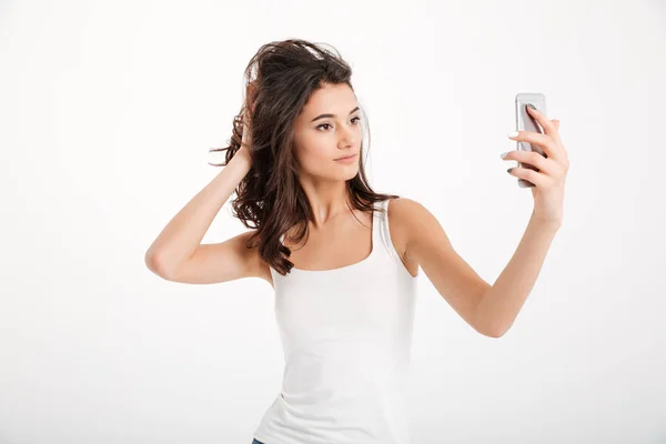 Portrait of a pretty girl dressed in tank-top taking a selfie — Stock Photo, Image