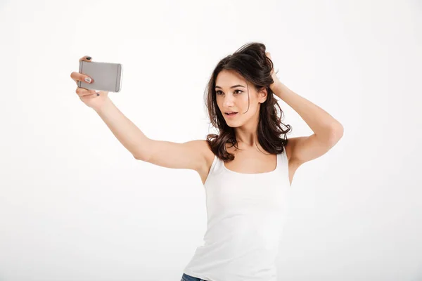 Portrait of a sensual girl dressed in tank-top taking a selfie — Stock Photo, Image