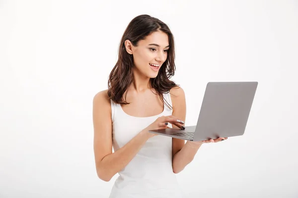 Retrato de una chica bonita vestida con camiseta sin mangas usando laptop — Foto de Stock