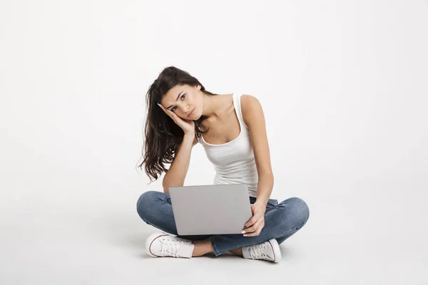 Portrait of an upset girl dressed in tank-top holding laptop — Stock Photo, Image