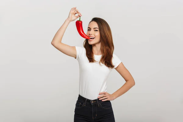 Portret van een mooie jonge vrouw bijten chili peper — Stockfoto