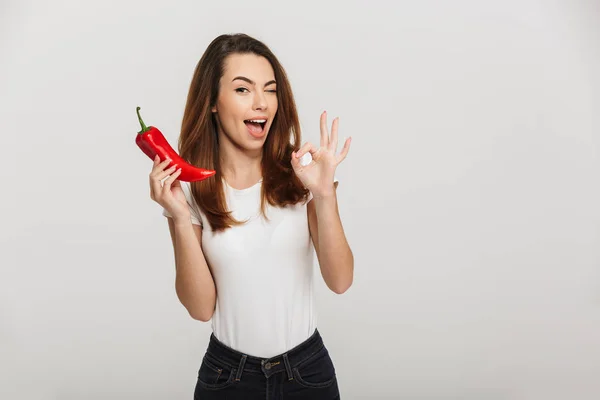 Portrait of a cheerful young woman holding chili pepper — Stock Photo, Image