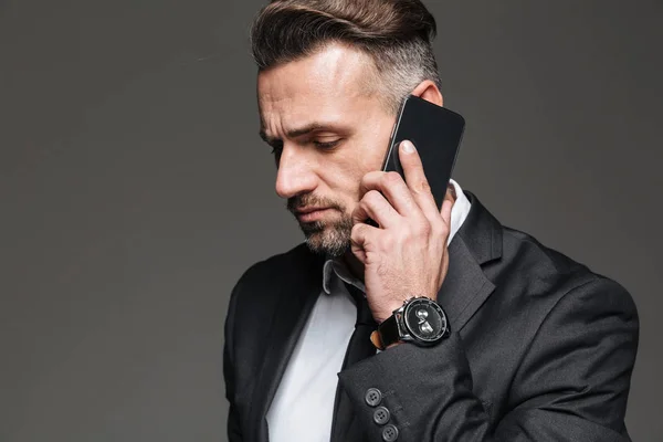 Portrait of businesslike guy in black suit talking on smartphone — Stock Photo, Image