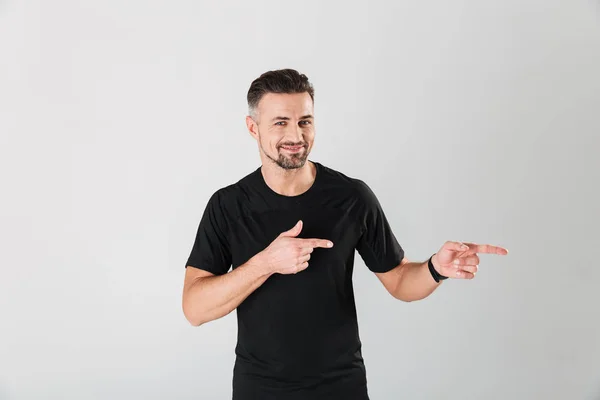 Retrato de um jovem desportista sorridente apontando os dedos para longe — Fotografia de Stock