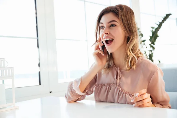Happy blondy woman in blouse sitting by the table — Stock Photo, Image