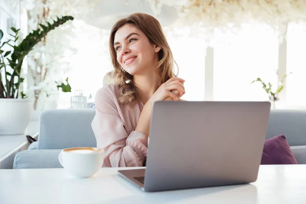 Portréja egy vidám fiatal nő ül a laptop számítógép — Stock Fotó