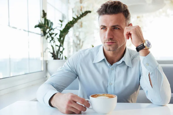 Imagen del hombre masculino de 30 años sentado solo en la cafetería de la ciudad con taza o —  Fotos de Stock