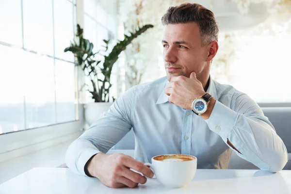 Retrato del hombre guapo sentado solo en la cafetería de la ciudad con una taza de —  Fotos de Stock