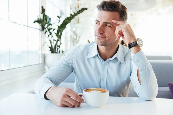 Foto de hombre masculino de 30 años sentado solo en la cafetería de la ciudad con taza o —  Fotos de Stock