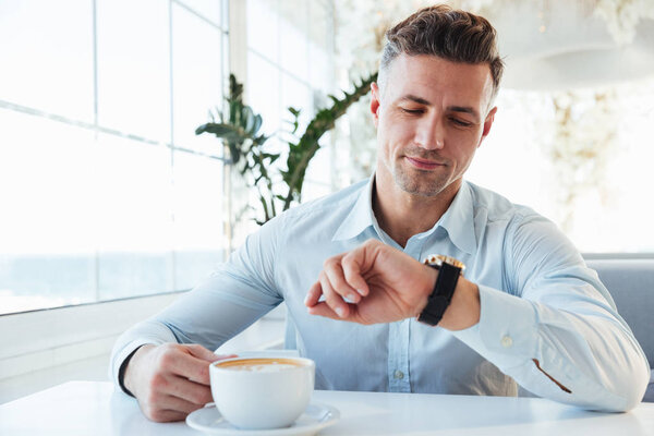 Изображение брюнетки мужчины с щетиной, сидящего в одиночестве в городском кафе
 