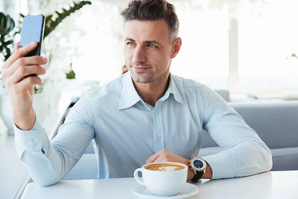 Sonriendo elegante hombre maduro descansando solo en la cafetería con taza de café —  Fotos de Stock