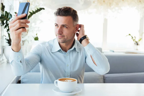 Glimlachend Kaukasische volwassen man alleen rusten in café met kop c — Stockfoto