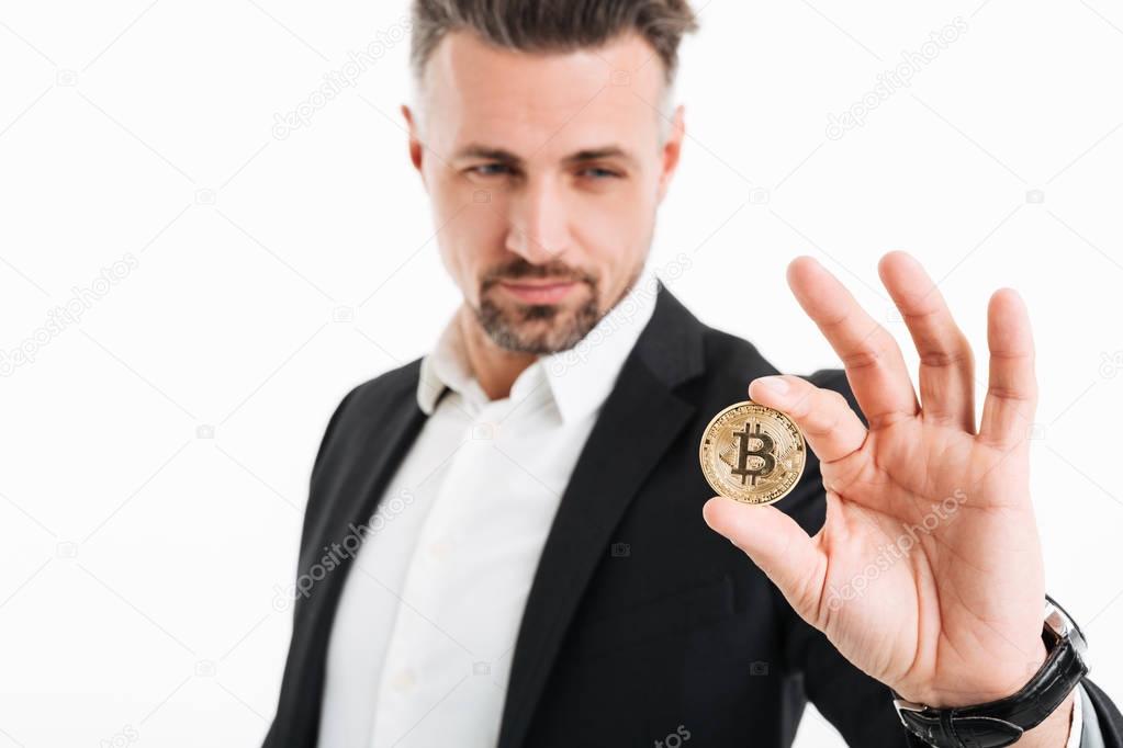 Photo of handsome rich businessman in suit showing golden bitcoi