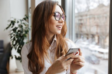 Cep telefonuyla chat yapan genç neşeli iş kadını