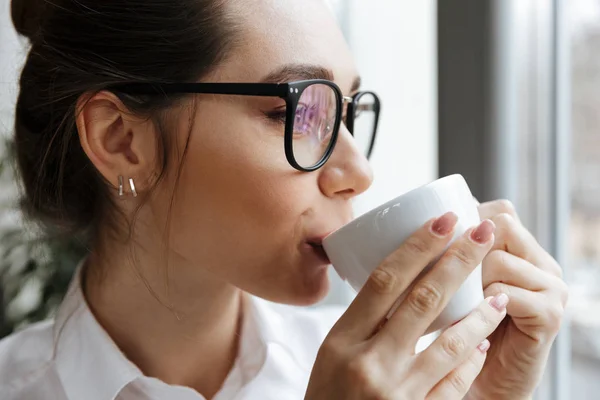 Mujer alegre de negocios sentada en el interior bebiendo café — Foto de Stock